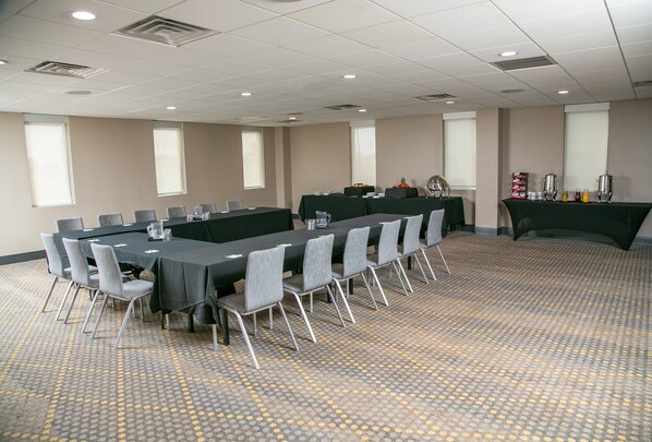 Une salle de conférence équipée d’une longue table, de chaises et d’un buffet garni de plats et de boissons.