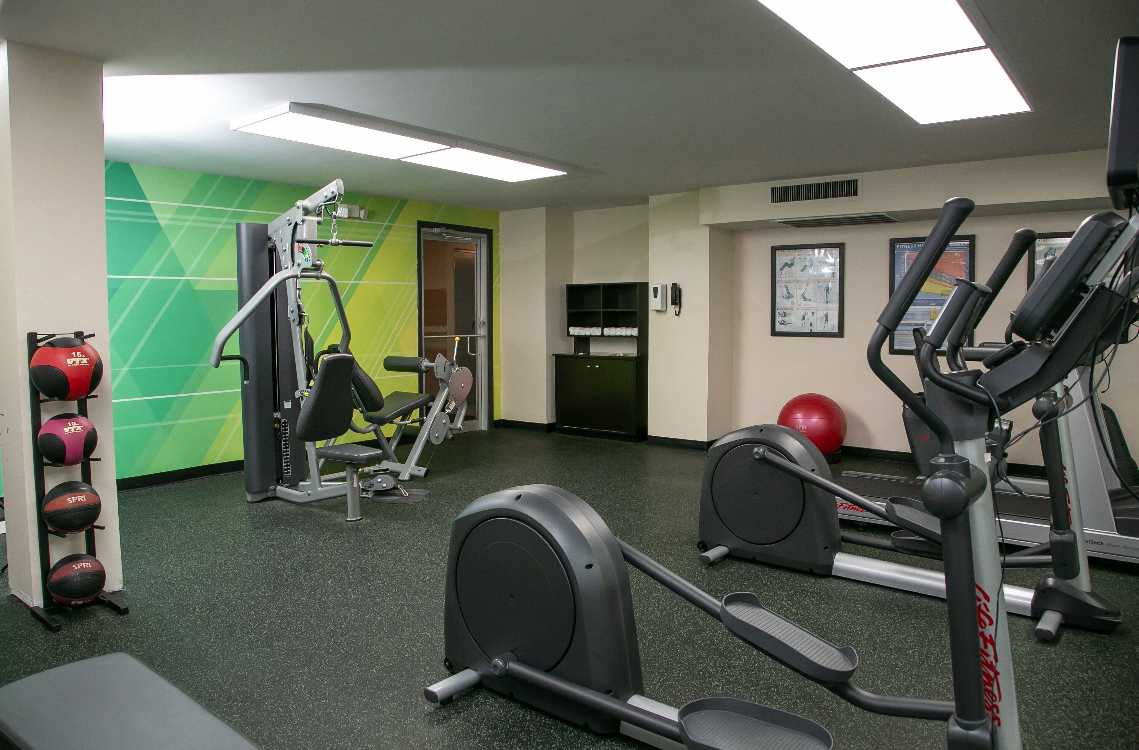 Ett gym med träningsutrustning, en grön vägg och en dörr.