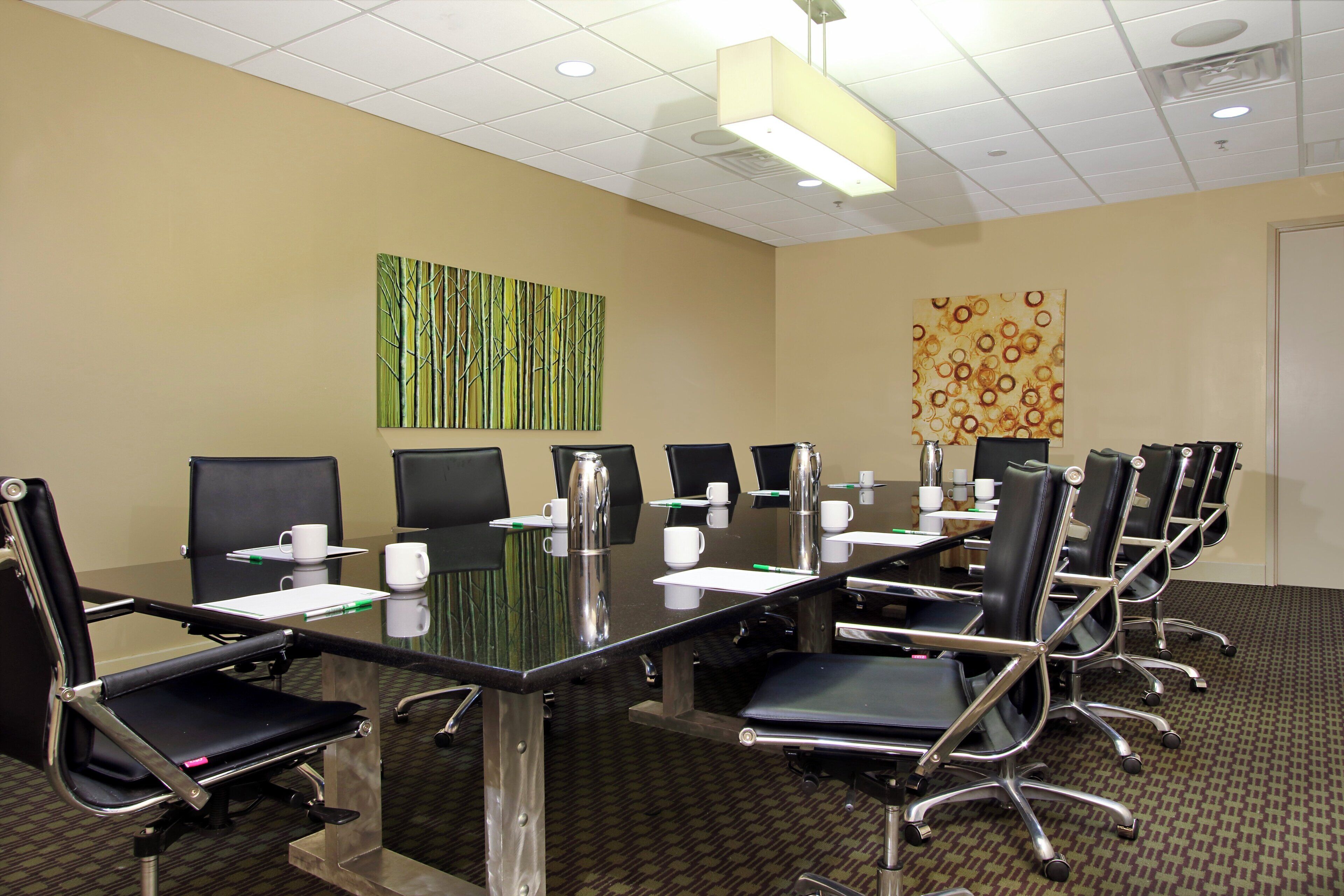 A conference room with a glass table, black chairs, and a patterned carpet.