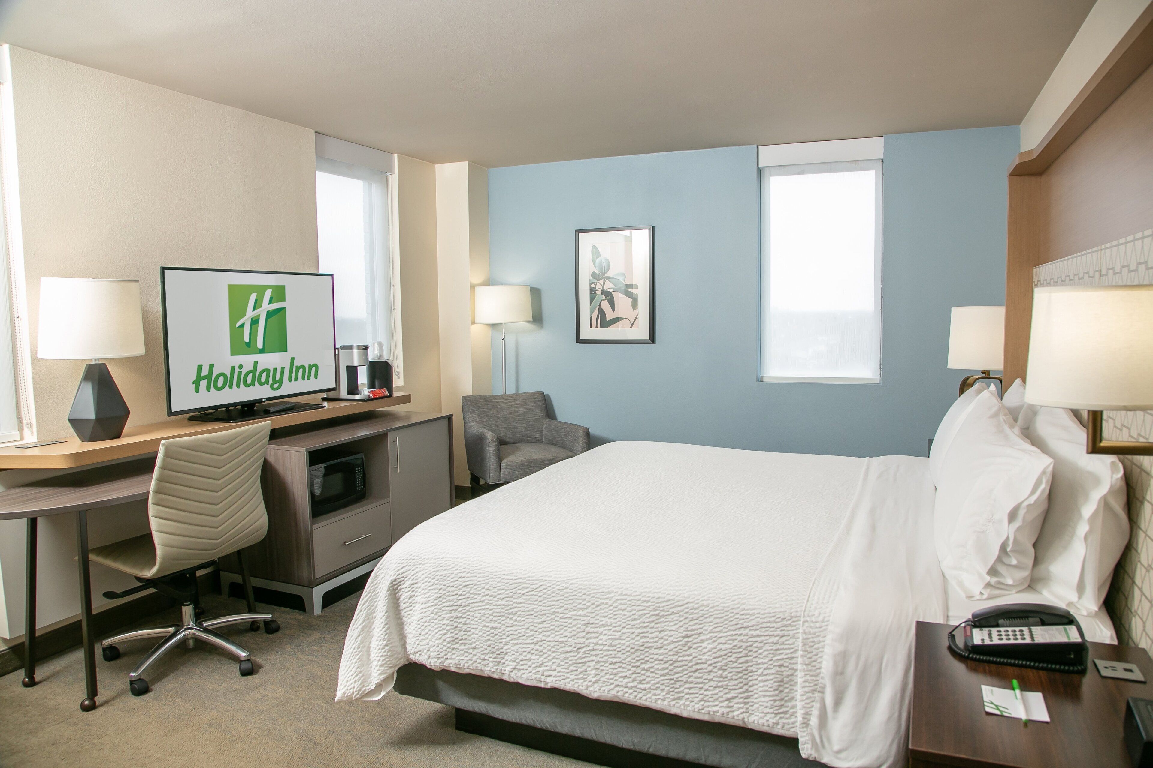 Une chambre d’hôtel équipée d’un lit, d’un bureau, d’une chaise, d’une télévision et d’un téléphone.
