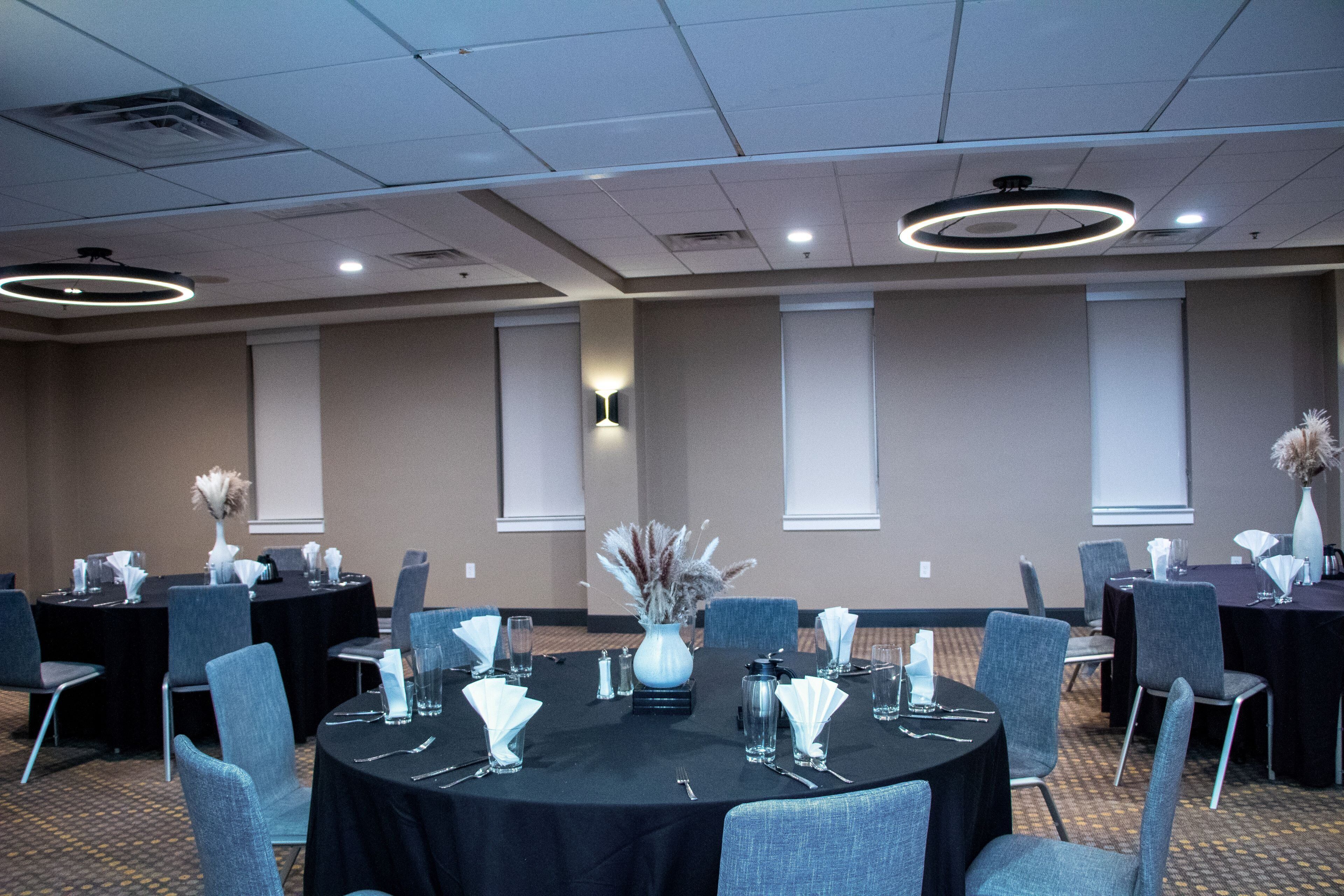 A conference room with round tables, chairs, and centerpieces.