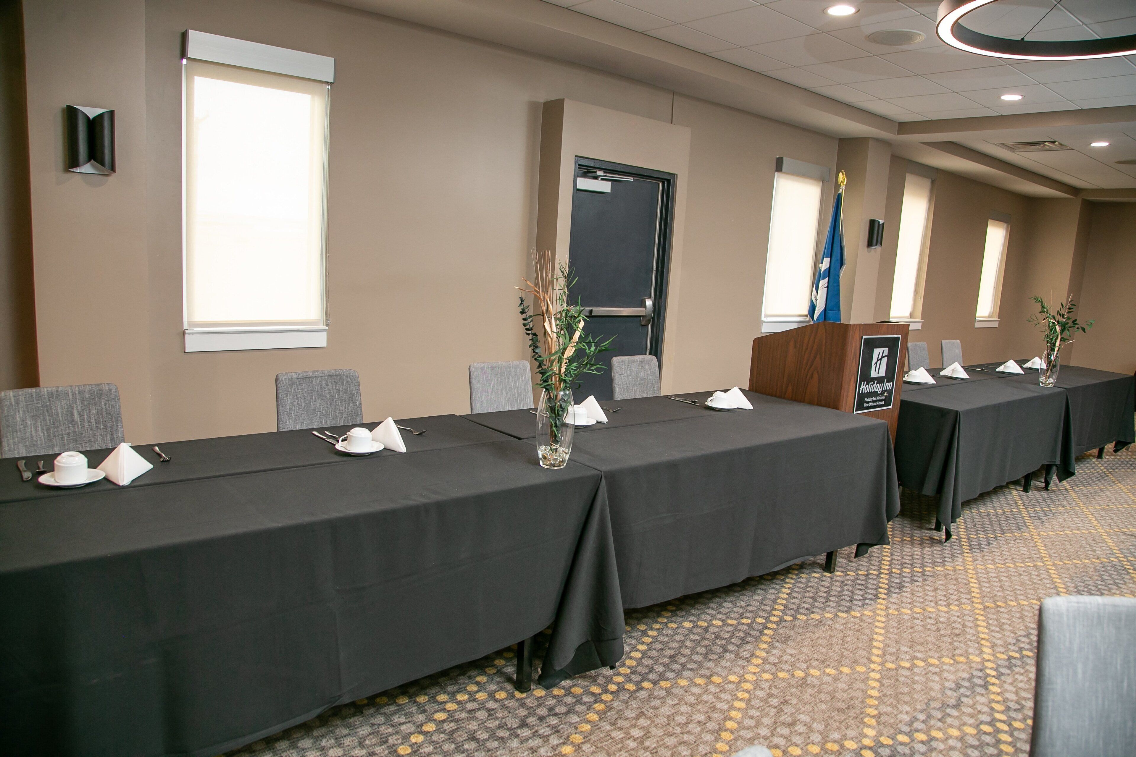 A conference room with long tables, chairs, and a podium.