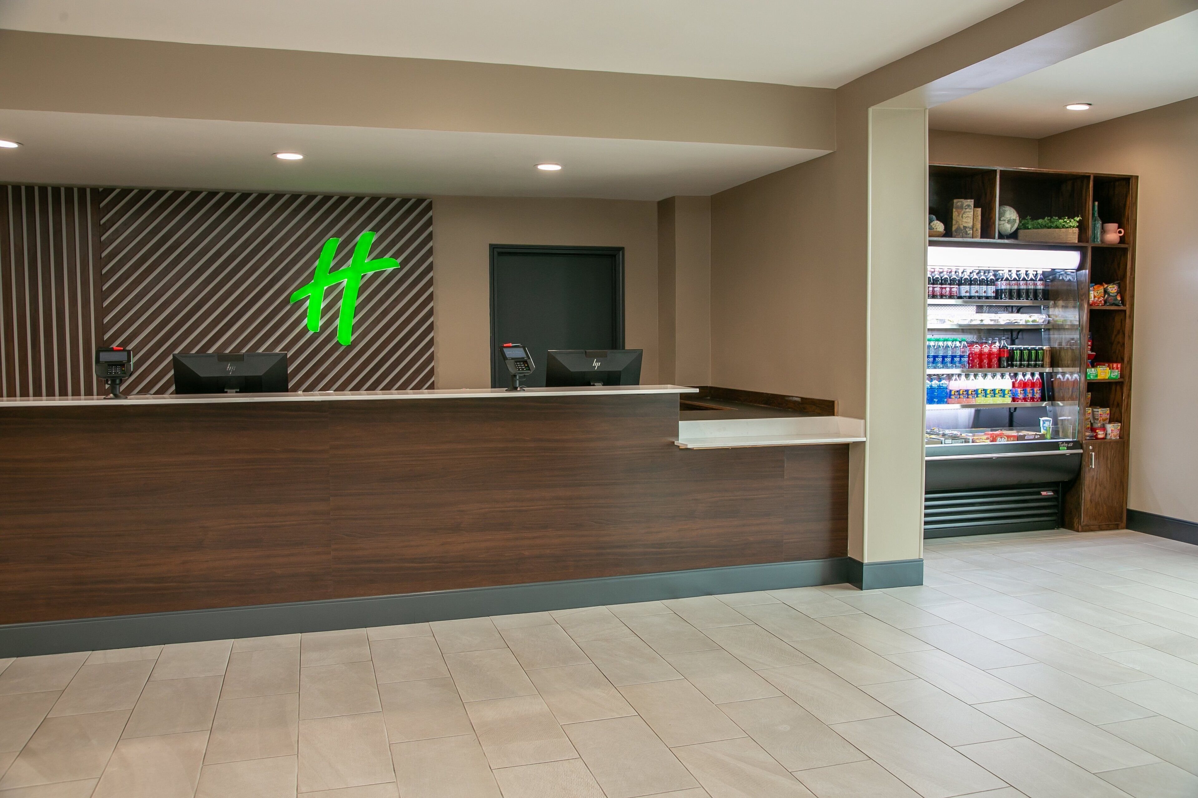 A reception area with a wooden reception desk, a digital phone, and a beverage refrigerator stocked with drinks.