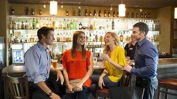 Eine Bar mit mehreren Hockstühlen und einer Auswahl an Flaschen in Regalen.
