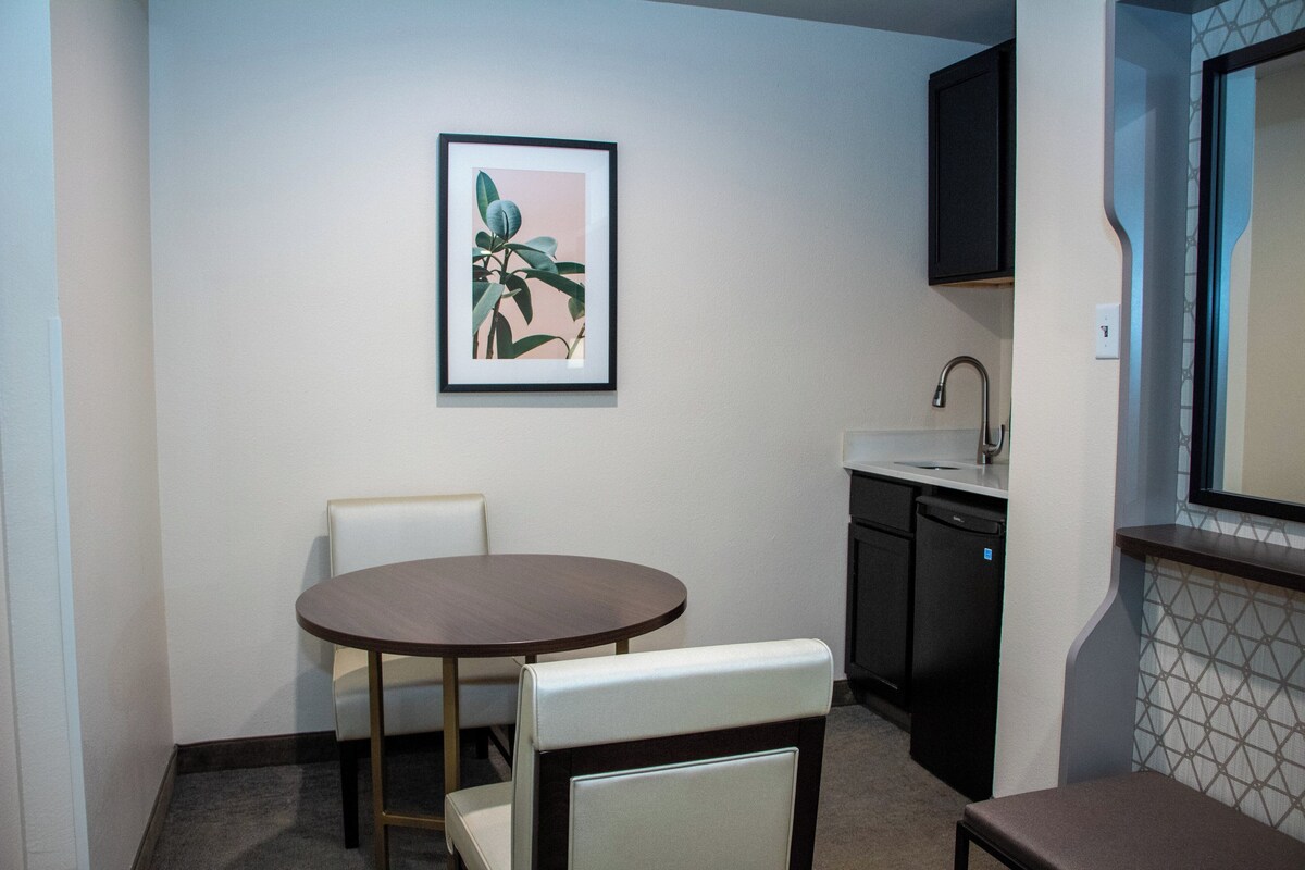 Cocina compacta con comedor, que incluye una mesa, sillas, un lavamanos y un lavavajillas.