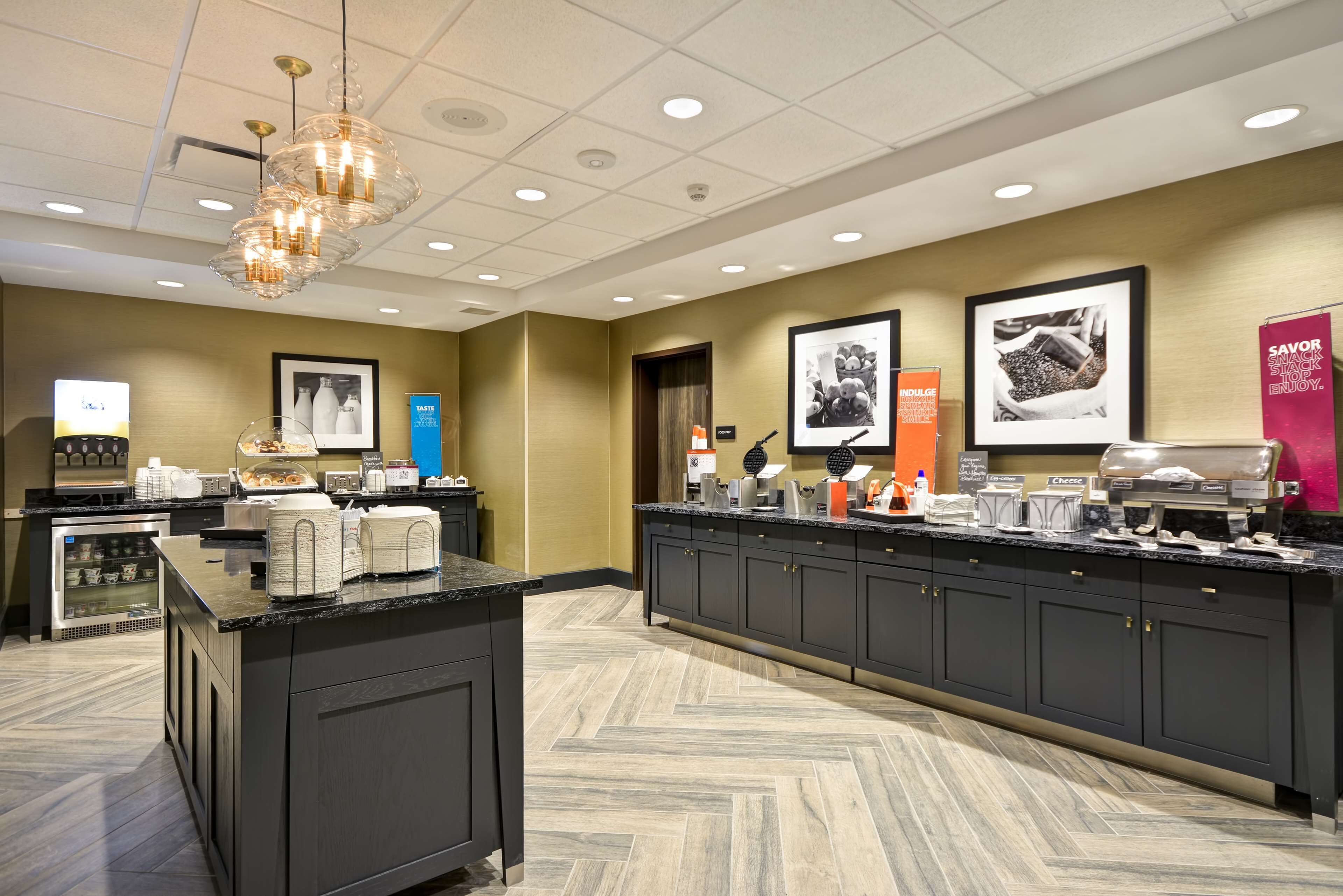 A hotel kitchen with a marble countertop, a large island, and a herringbone-patterned floor.