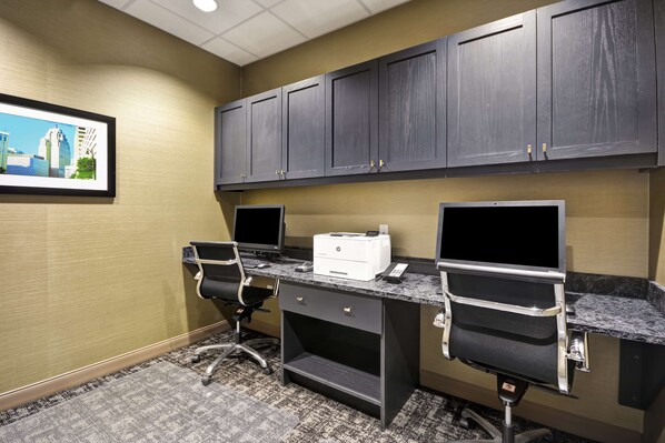 A hotel office with two desks, chairs, a printer, and a framed cityscape picture on the wall. - Hampton Inn & Suites Detroit/Warren (Warren)