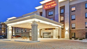 Een Hampton Inn & Suites met een overdekte ingang, gevel van baksteen en een goed verlicht bord.