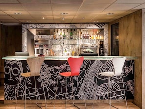 A bar area with a counter, bar stools, and a variety of bottles and glasses. - ibis Paris Gare du Nord la Fayette 10ème (Paris)