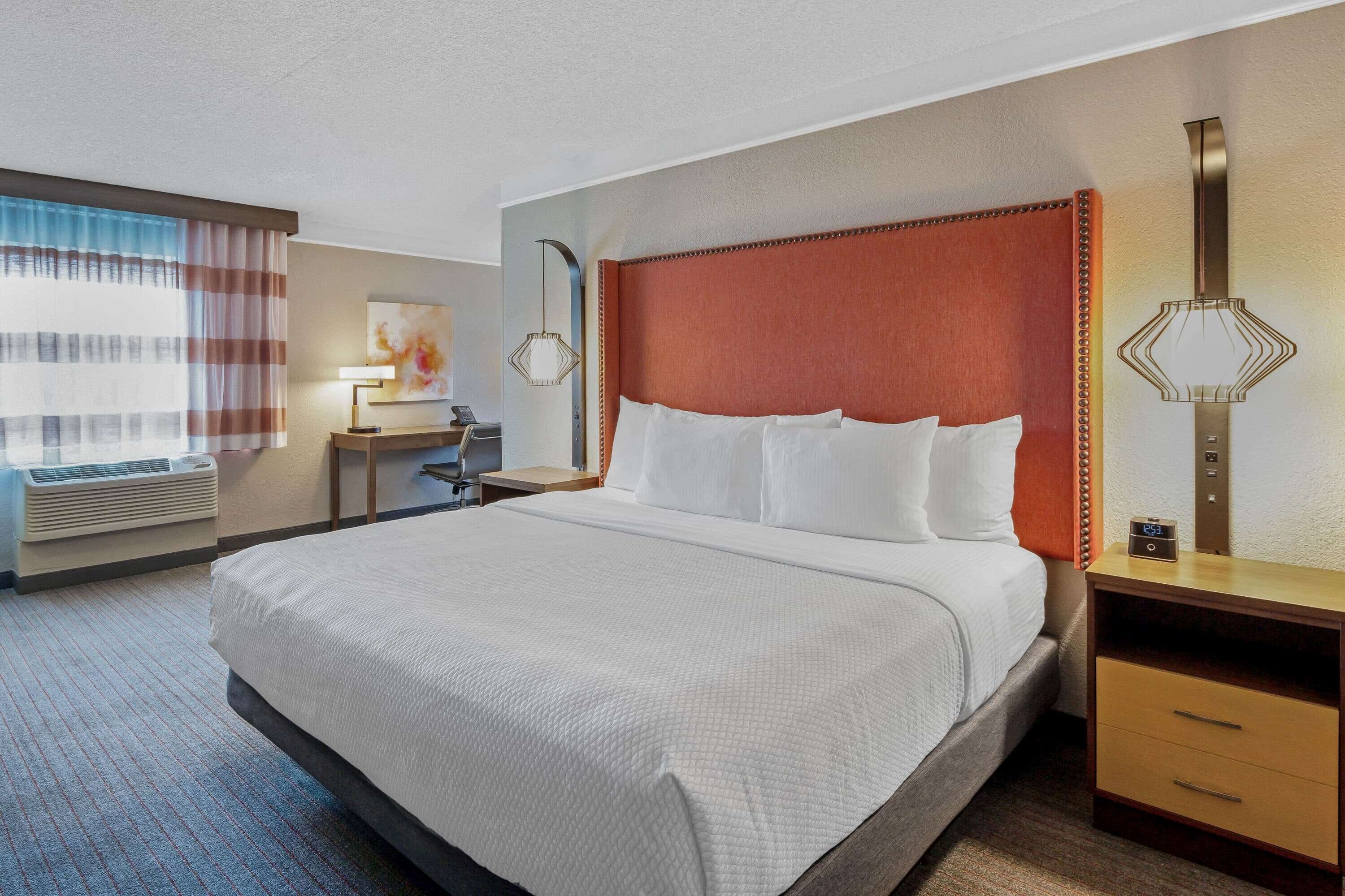 Una habitación de hotel con una cama grande, un escritorio, una lámpara y una mesita de noche.