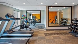 Une salle de sport équipée de tapis de course, d’un vélo de spinning et de divers appareils d’exercice.