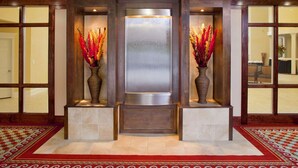 A reception area with a central glass partition, two vases with dried flowers, and a patterned carpet.