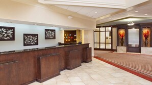 A reception area with a marble counter, decorative wall art, and a patterned carpet.