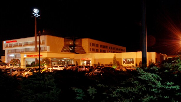 A hotel with a parking lot and a sign for 'DoubleTree Hotel'.