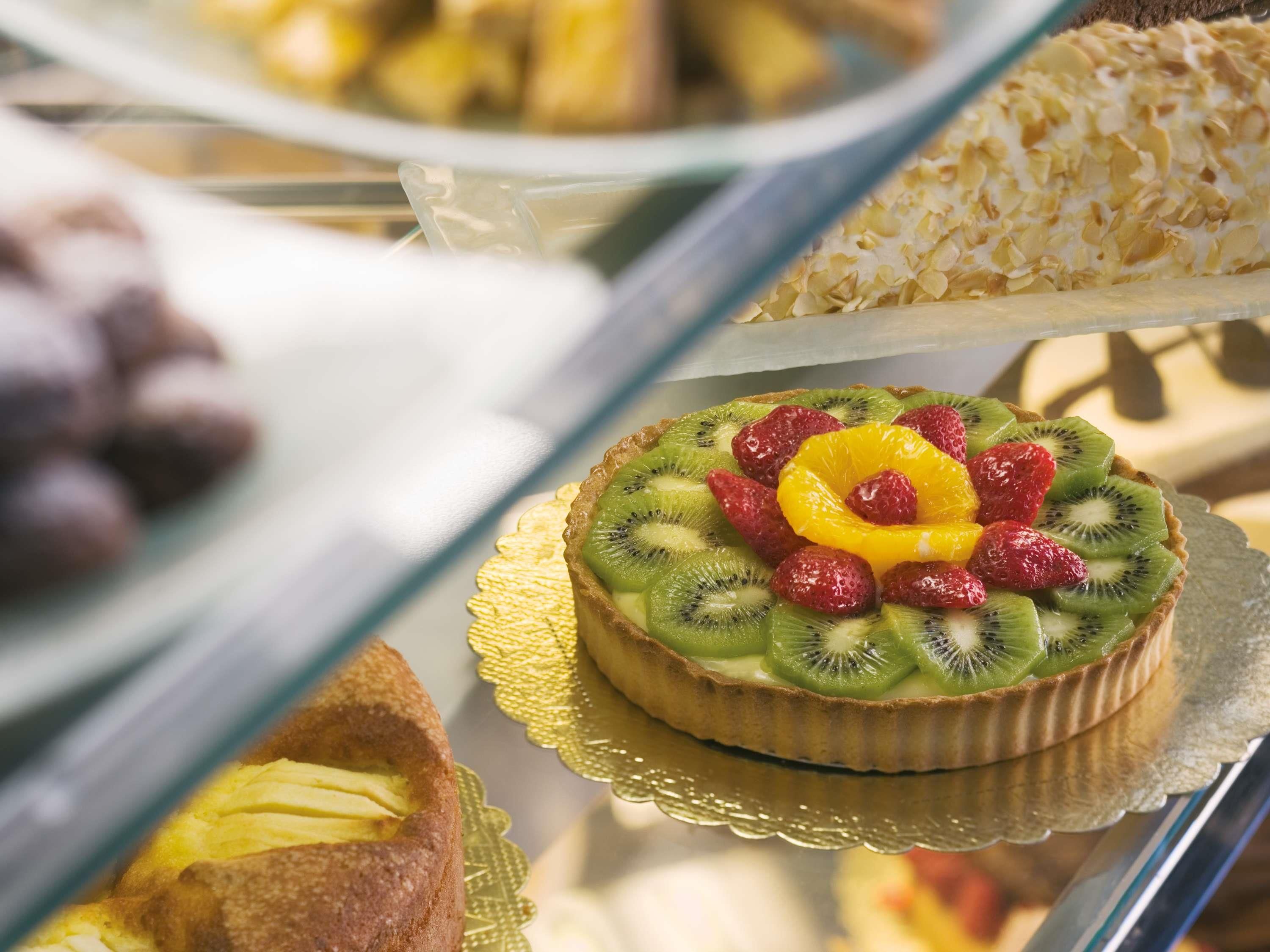 A dessert display with a tart topped with kiwi, strawberries, and orange slices.