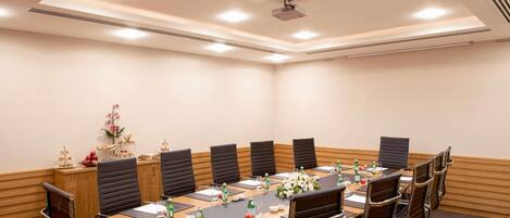 A conference room with a long table, chairs, and a projector.