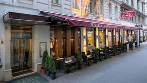 Exterior del hotel Graben con mesas al aire libre y una pizzería llamada Trattoria Santo Stefano.