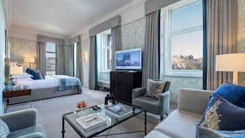 Een hotelkamer met een bed, een bank, een bijzettafeltje, een televisie en uitzicht op een stadsbeeld.