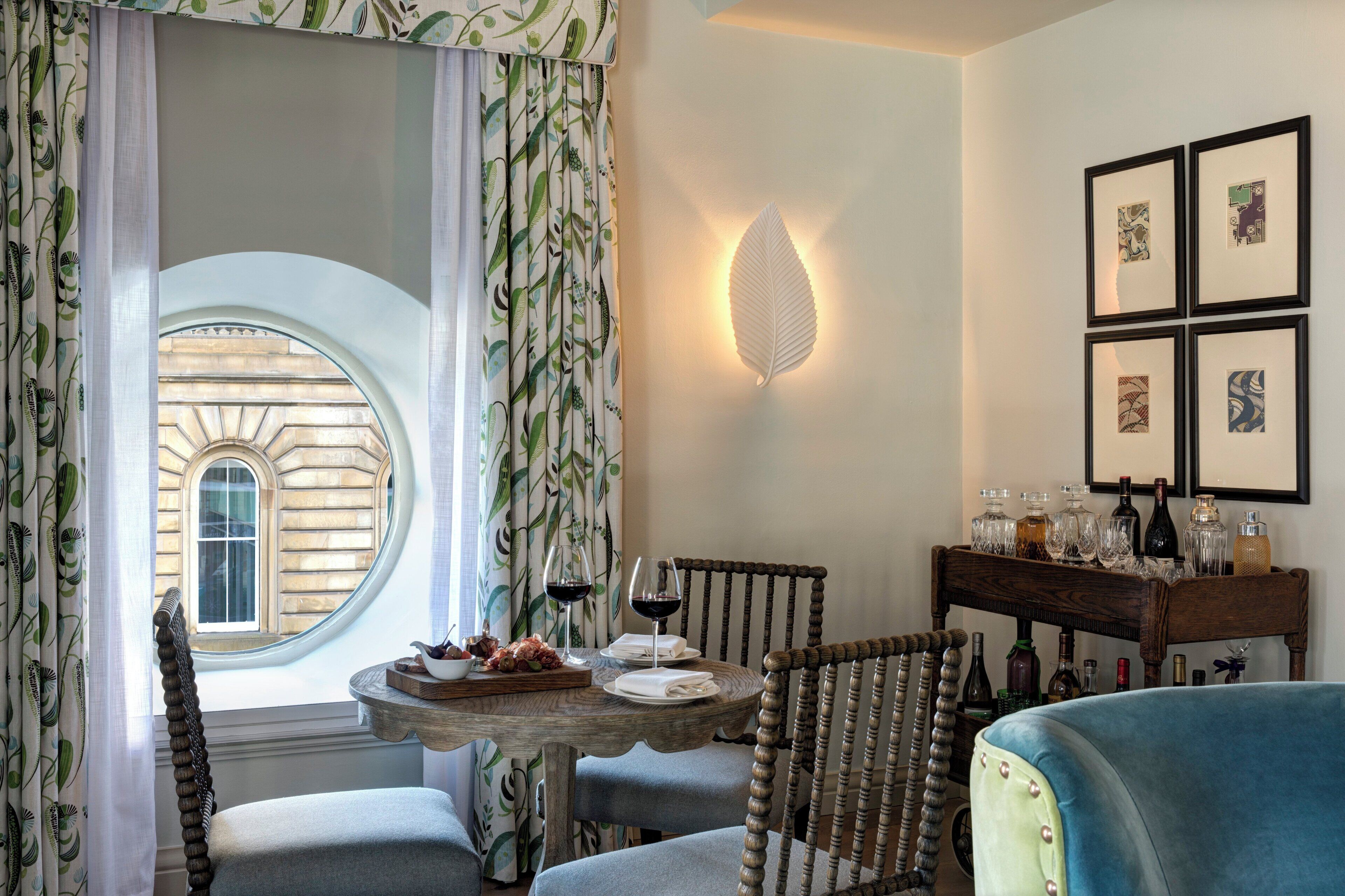 A dining area with a round table, chairs, and a view through a window.