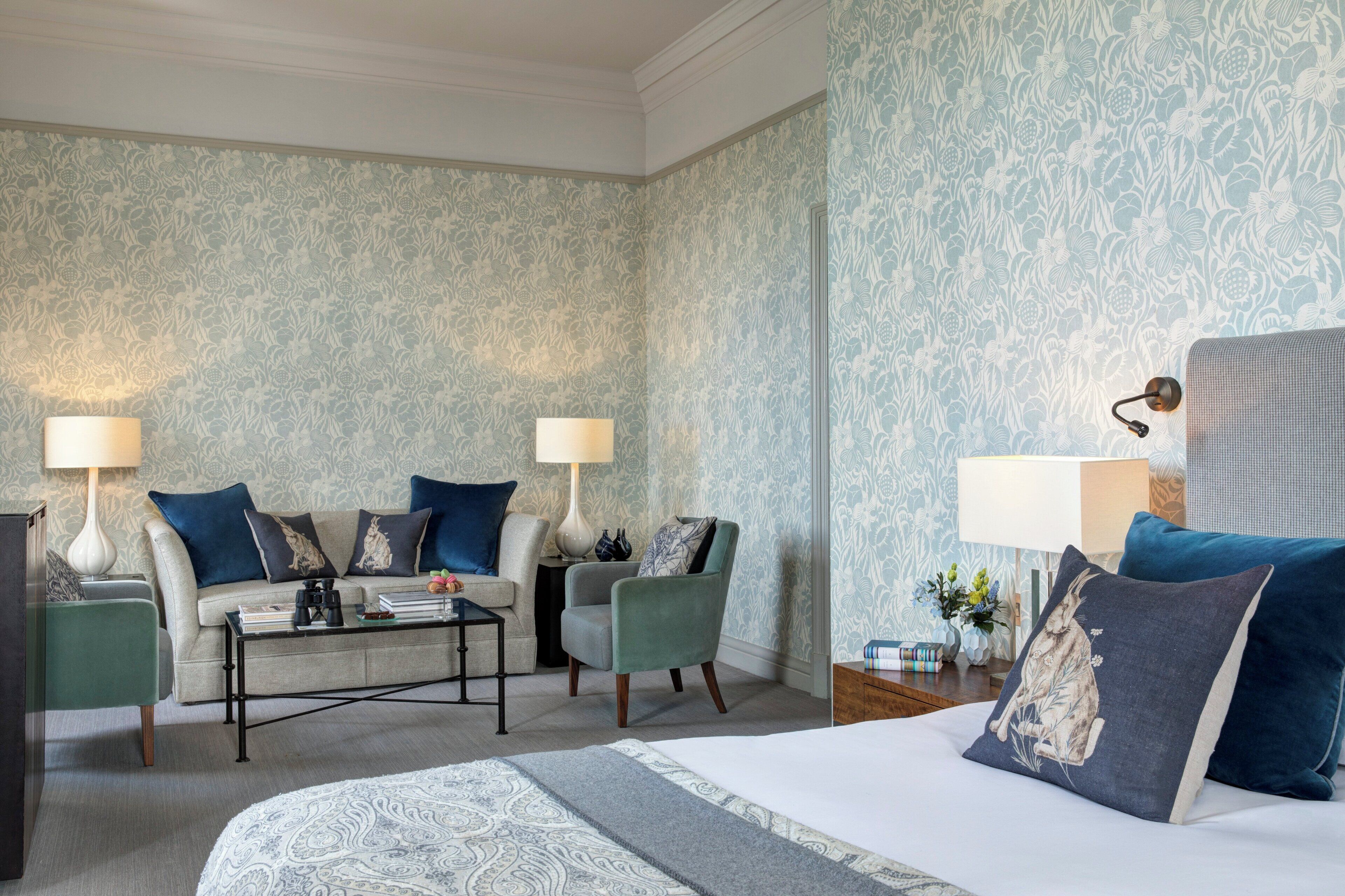 Ett hotellrum med en säng, två fåtöljer, en soffa, ett soffbord och två lampor.