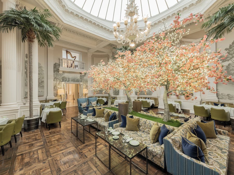Ein großzügiger Speisesaal mit hoher Decke, aufwendigen Säulen und einer üppigen Blumendekoration.
