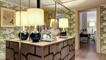 A well-lit room with a wooden cabinet, two lamps, a bust sculpture, and a vase with flowers.