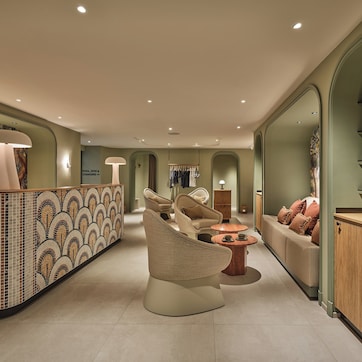 A modern interior with a reception desk, seating area, and a mirrored wall.