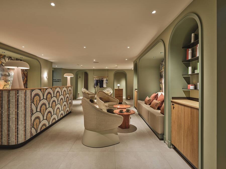 Un intérieur moderne comprenant un comptoir d’accueil, un espace salon et un mur recouvert de miroirs.
