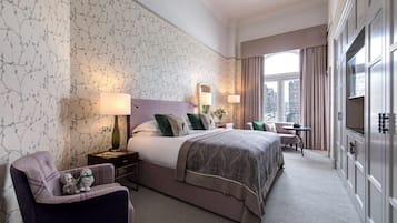 Habitación de hotel con una cama grande, un escritorio, una silla y un televisor.