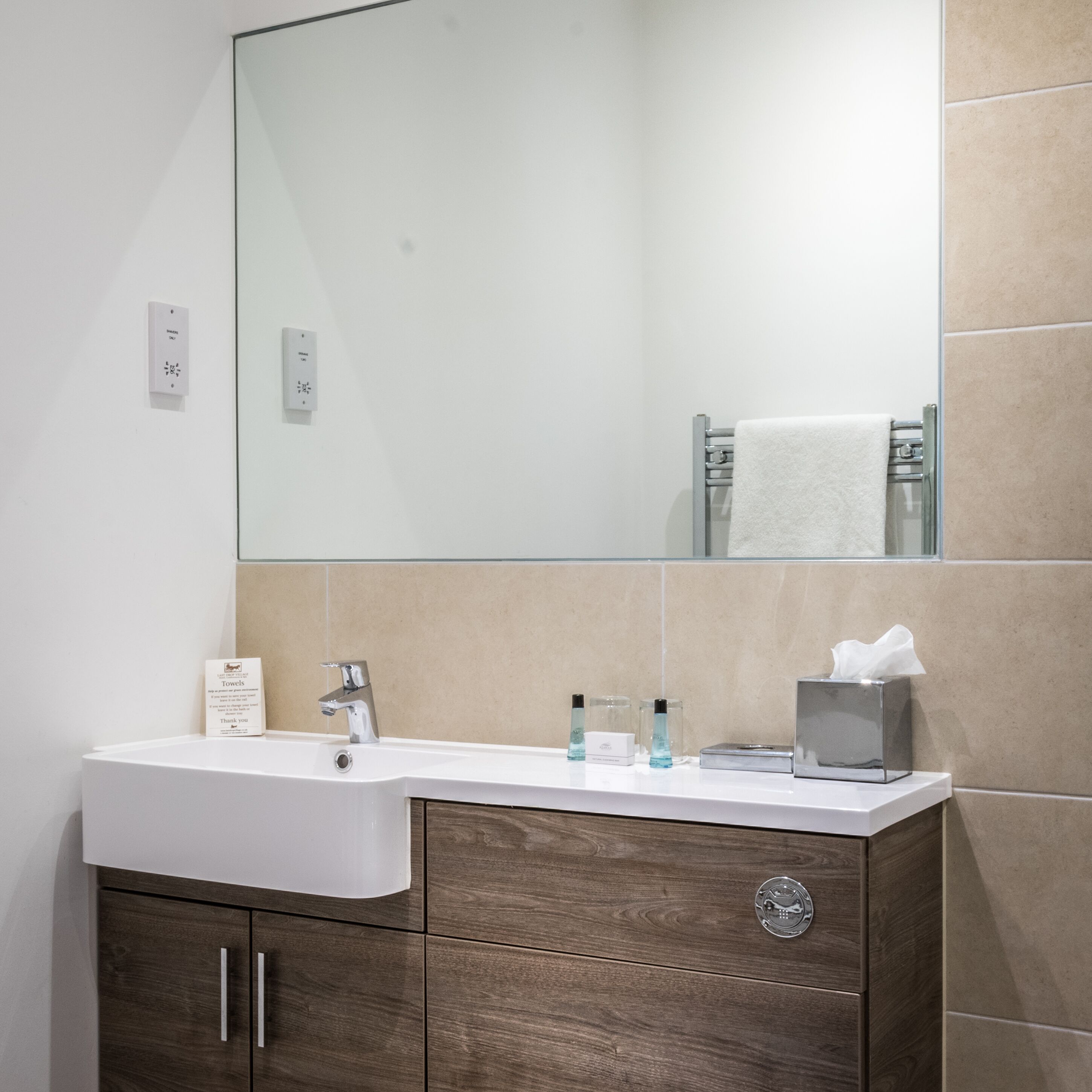 Un baño moderno con un espejo grande, un lavamanos blanco y un mueble de tocador de madera.