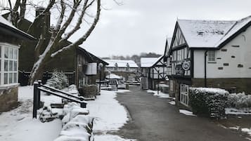 A narrow snow-covered street in a traditional village with stone buildings and a pub.