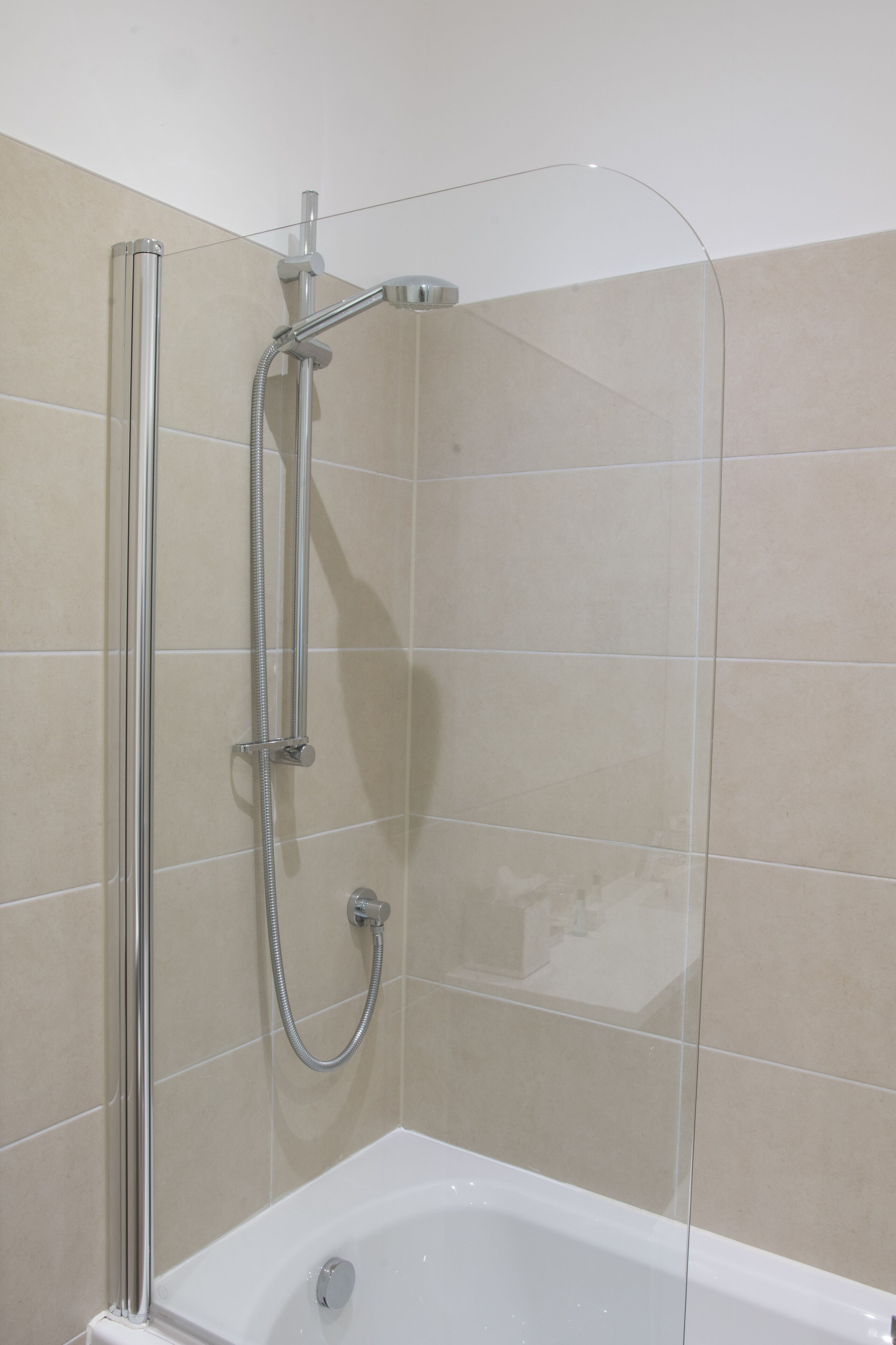 Douchecabine met een glazen deur, een handdouche en een wandmengkraan.