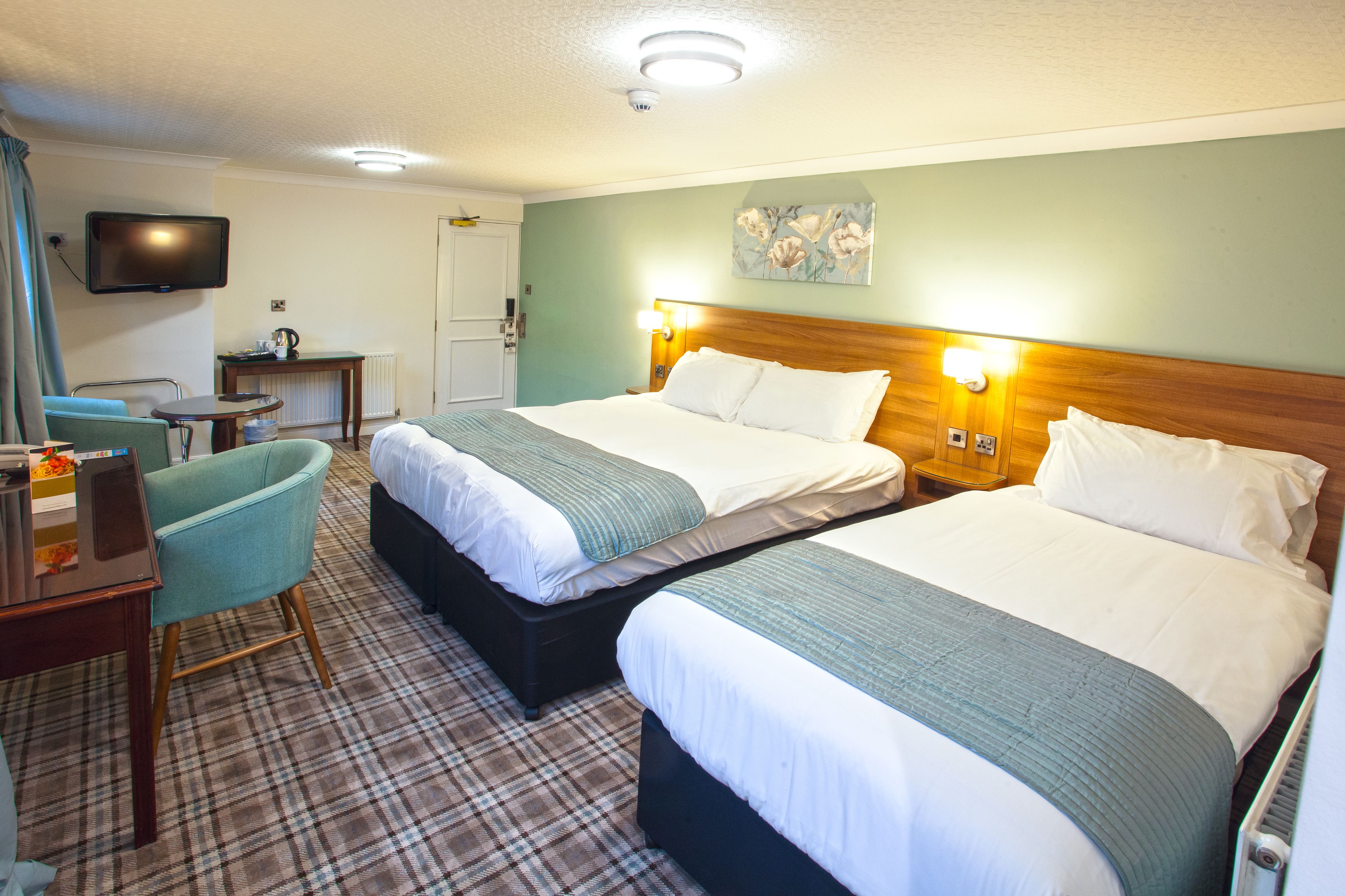 A hotel room with two beds, a TV, a desk, and a chair.
