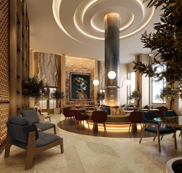 Um lobby moderno com área de estar central, um mural grande e uma luminária cilíndrica marcante.