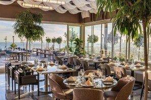 A restaurant with tables set for dining, large windows offering a view, and hanging plants. - Radisson Hotel President Old Town Istanbul (Istanbul)