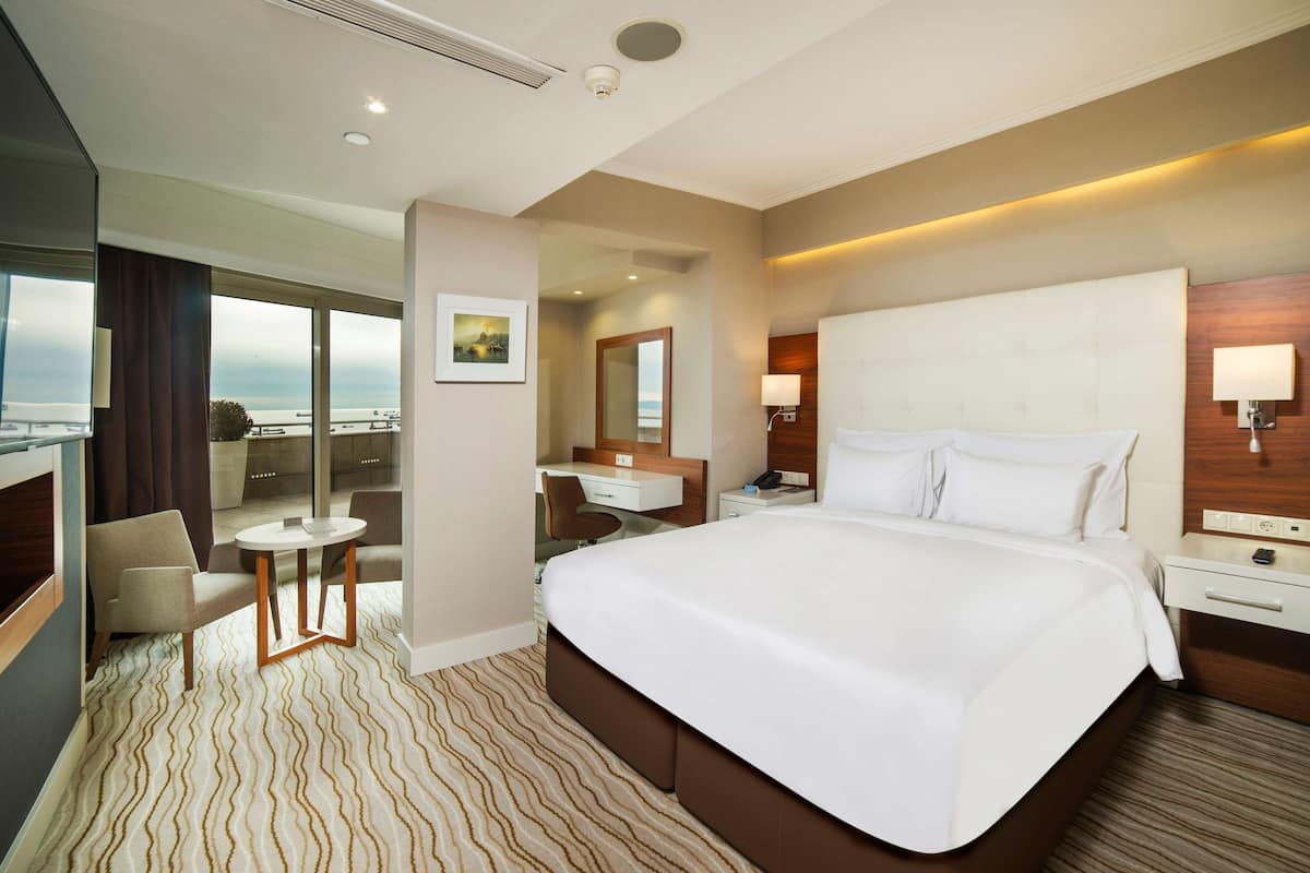 Una habitación de hotel moderna con una cama grande, un escritorio, una silla y vistas a la ciudad.