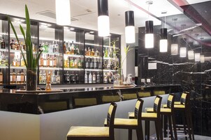 A bar area with a marble countertop, shelves of liquor bottles, hanging pendant lights, and bar stools.