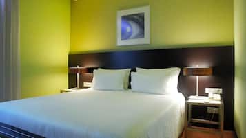 A hotel room with a large bed, two bedside tables with lamps, a wall-mounted artwork, and a nightstand with a phone.