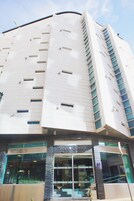 A modern building with a curved facade, large windows, and a sign reading "SANA CAPITOL."