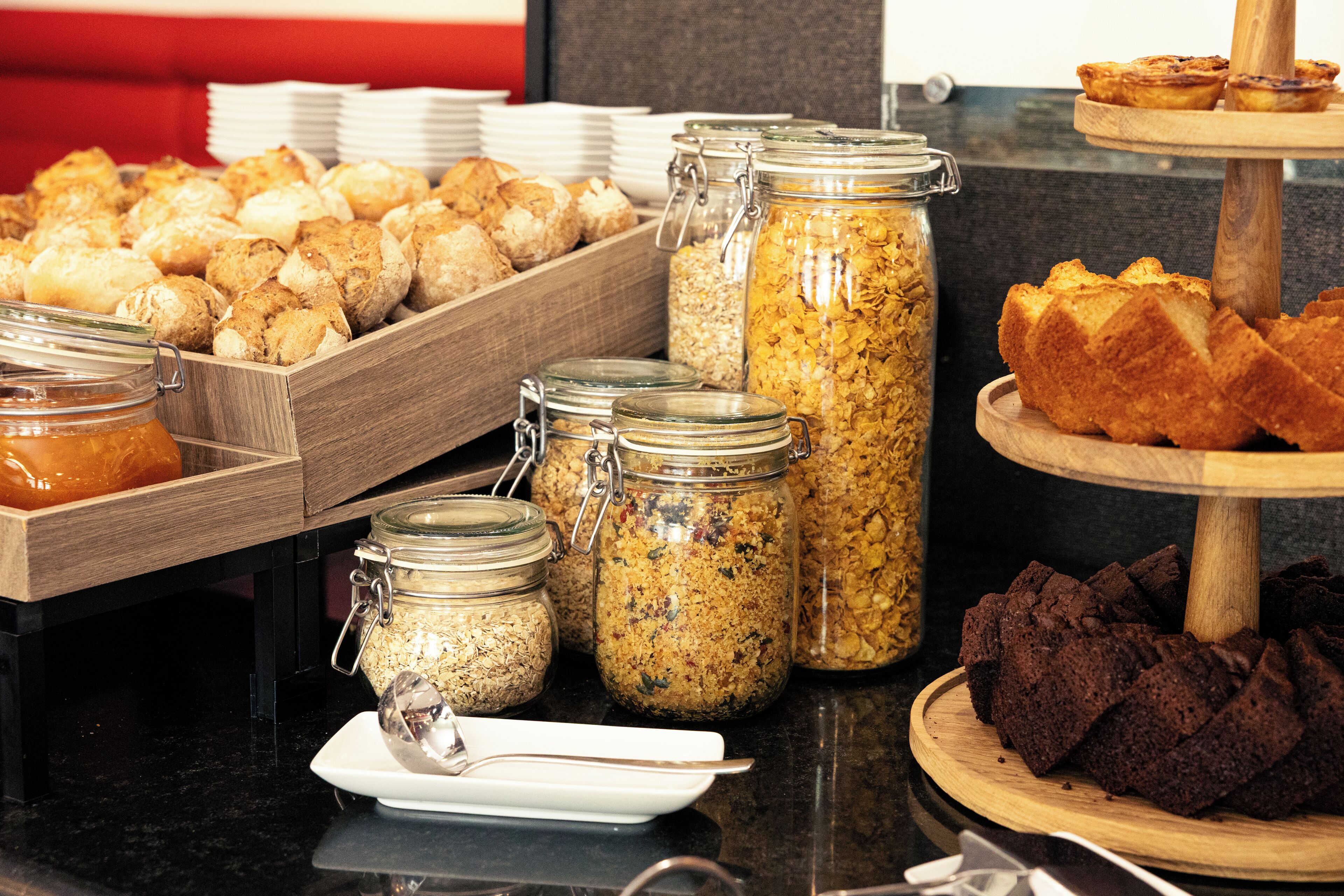A buffet with various food items including pastries, bread, and jars of spreads.