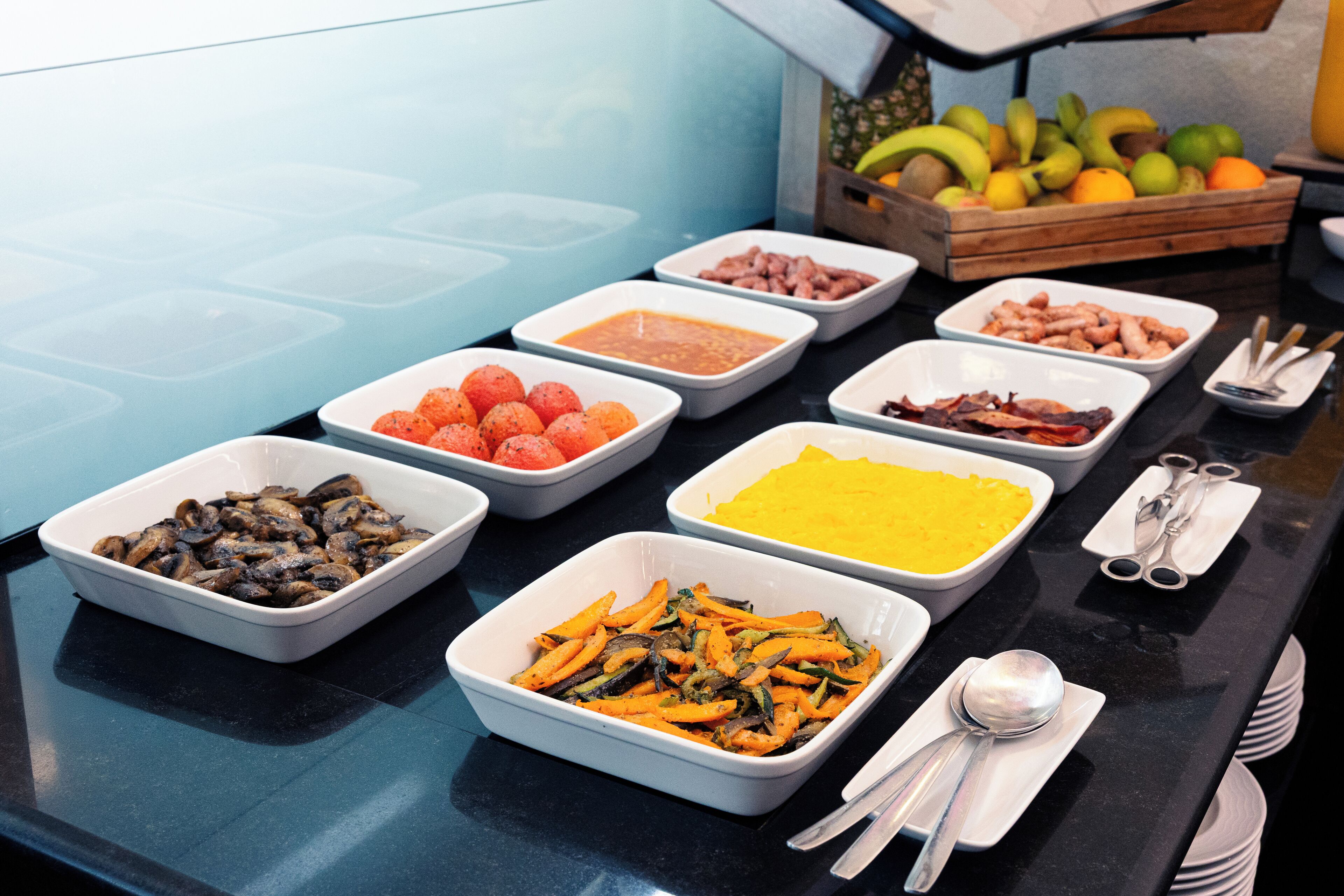 A buffet with various food items including fruits, vegetables, and meats.
