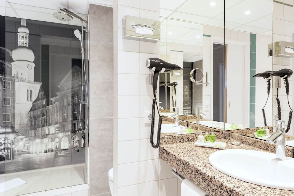 Un baño moderno con un espejo grande, un secador de pelo y un lavamanos.