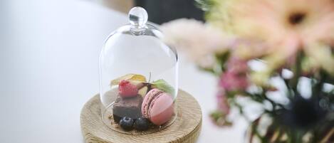 A dessert under a glass dome on a wooden coaster.