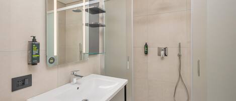A modern bathroom with a white sink, a glass shower enclosure, and a handheld showerhead.
