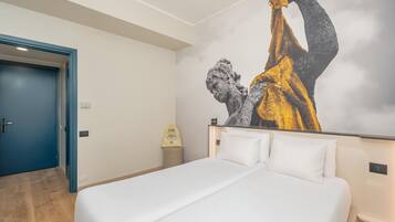 Habitación de hotel con cama, una puerta azul y un cuadro grande en la pared.