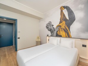 A hotel room with a bed, a blue door, and a wall with a large artwork. - B&B Hotel Como City Center (Como)