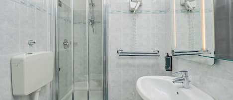 Un baño con ducha de vidrio, inodoro y lavamanos.