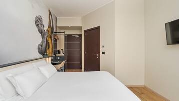 Una camera d'albergo con un letto, una scrivania, uno specchio, un armadio e una televisione.