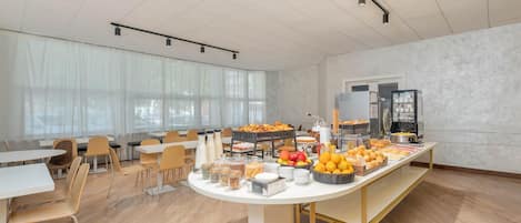 Amplia habitación con una larga mesa dispuesta para el desayuno, mostrando diversas comidas y bebidas.