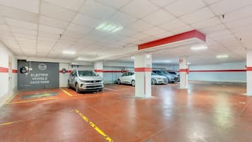 A parking garage with multiple levels, marked parking spaces, and a sign indicating reserved spots for electric vehicles.